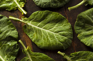 Image of fresh collard green leaves on a rustic wooden surface.